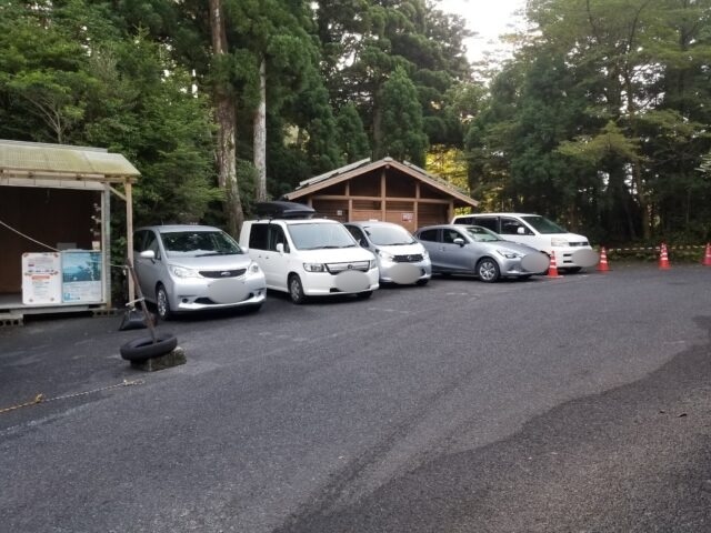 淀川登山口の駐車場に並ぶ車と、奥のトイレの建物