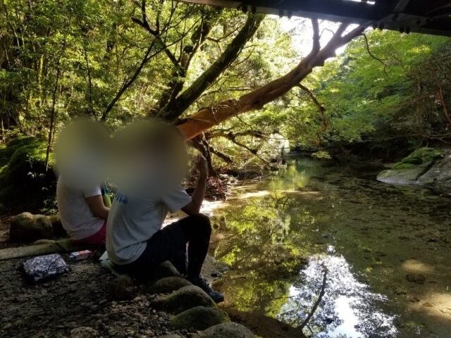 淀川のほとりの岩に腰かけて休む登山者